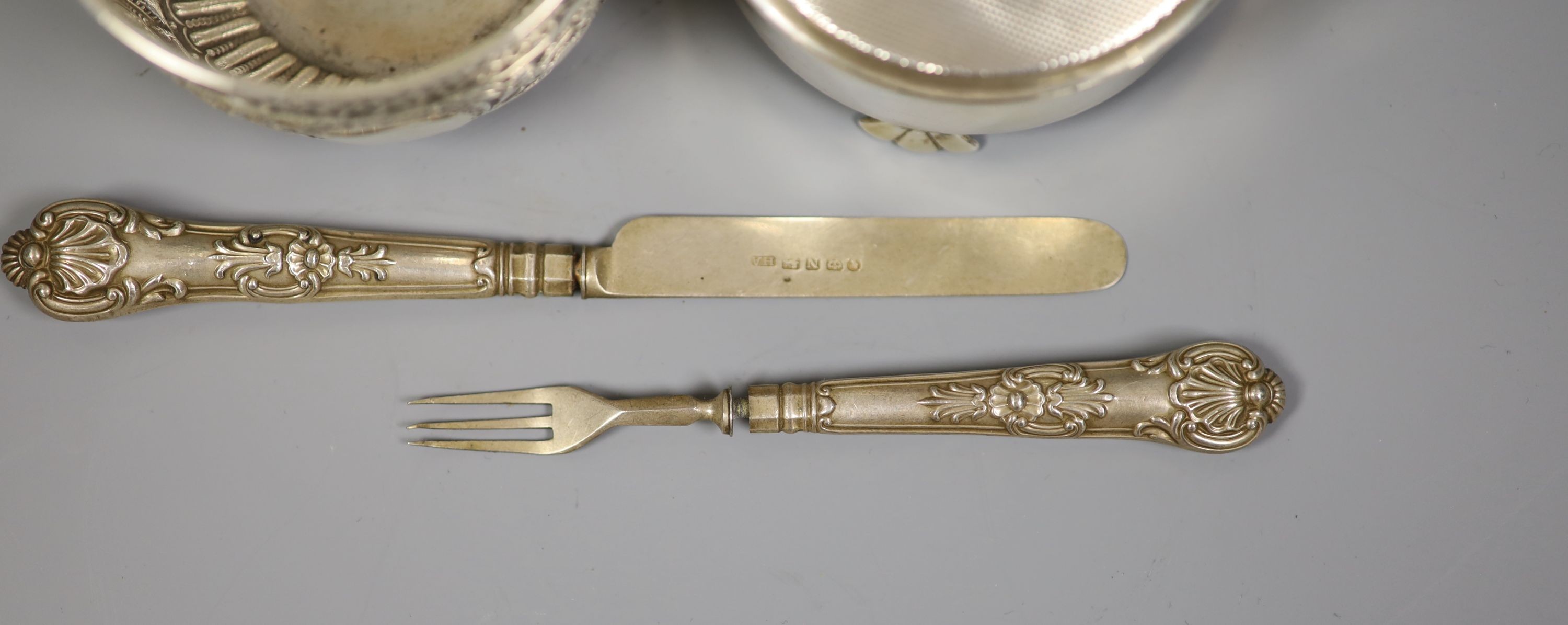 A late Victorian repousse silver bowl, London, 1898, diameter 8cm, a modern silver mounted circular trinket box, Birmingham, 1976 and a christening knife and fork, the knife with silver blade.